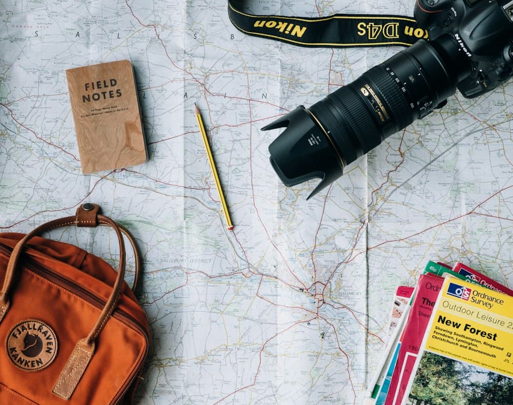 Carte routière, carnet, appareil photo et sac à dos pour préparer un long voyage